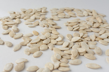 Roasted pumpkin seeds with salt on white background.