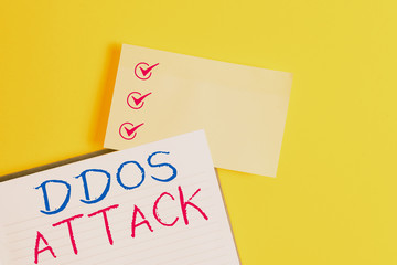 Conceptual hand writing showing Ddos Attack. Concept meaning perpetrator seeks to make a network resource unavailable to user Empty orange paper with copy space on the yellow table
