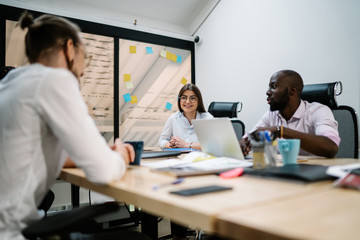 Fototapeta premium Successful male and female managers enjoying collaboration together in conference room, crew of cheerful people discussing ideas for business startup project and laughing during break in office
