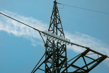 Electric transmission line tower with insulators and conductors. Closeup view on blue sky background. Concept of electric power supply, alternative energy and safety environment systems