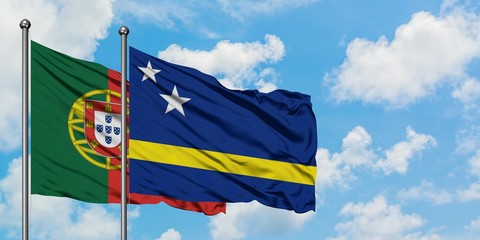 Portugal and Curacao flag waving in the wind against white cloudy blue sky together. Diplomacy concept, international relations.