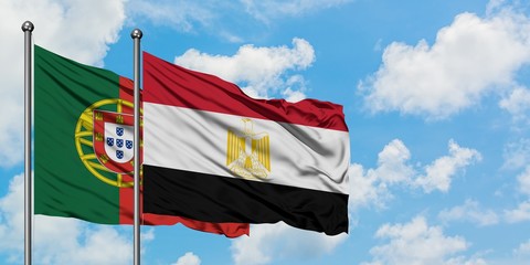 Portugal and Egypt flag waving in the wind against white cloudy blue sky together. Diplomacy concept, international relations.