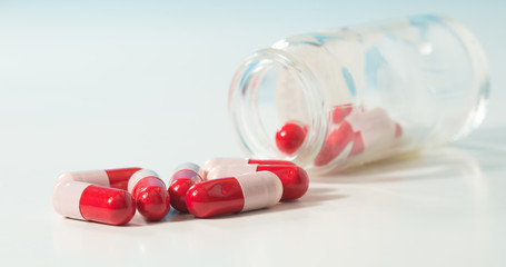 Glass bottle and group of antibiotic pills with reflection