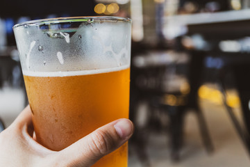 chill beer holding by hand on dark background and light bokeh