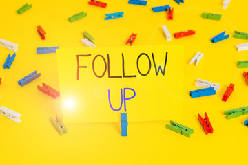 Text sign showing Follow Up. Business photo text a continuation of something that has already been started Colored clothespin papers empty reminder yellow floor background office