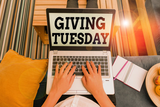 Conceptual hand writing showing Giving Tuesday. Concept meaning international day of charitable giving Hashtag activism woman with laptop smartphone and office supplies technology