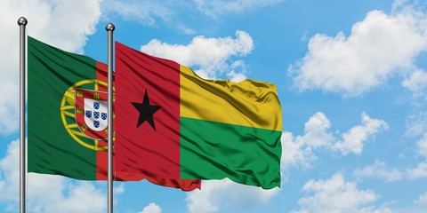 Portugal and Guinea Bissau flag waving in the wind against white cloudy blue sky together. Diplomacy concept, international relations.