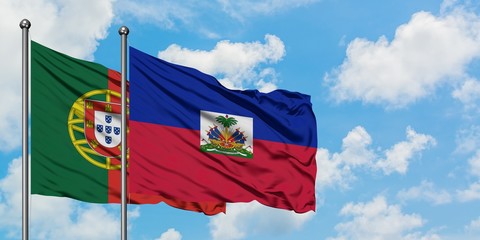 Portugal and Haiti flag waving in the wind against white cloudy blue sky together. Diplomacy...