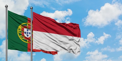 Portugal and Indonesia flag waving in the wind against white cloudy blue sky together. Diplomacy concept, international relations.