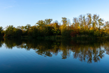 Fototapeta na wymiar Wunderbarer Herbst mit Bäumen am See und blauen Himmel