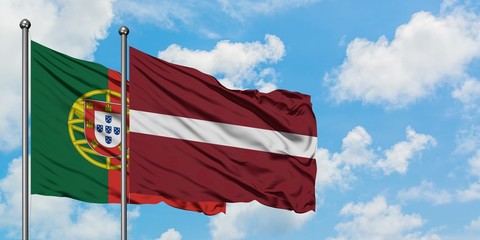 Portugal and Latvia flag waving in the wind against white cloudy blue sky together. Diplomacy concept, international relations.