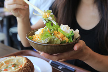 chiba, japan, 11/04/2019 , Woman eating  a salad on a bowl with chopsticks.