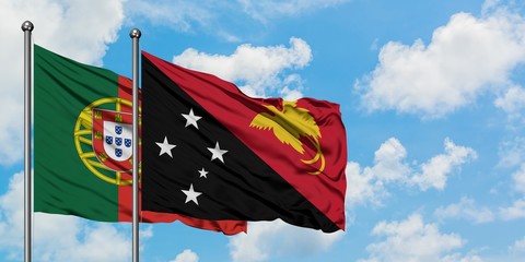 Portugal and Papua New Guinea flag waving in the wind against white cloudy blue sky together. Diplomacy concept, international relations.