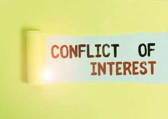 Text sign showing Conflict Of Interest. Business photo text disagreeing with someone about goals or targets Cardboard which is torn in the middle placed above a plain table backdrop
