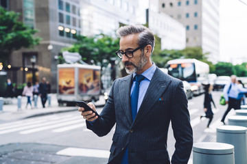 Businessman with smartphone on busy street