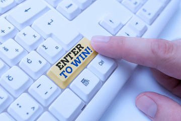 Conceptual hand writing showing Enter To Win. Concept meaning exchanging something value for prize or chance of winning White pc keyboard with note paper above the white background