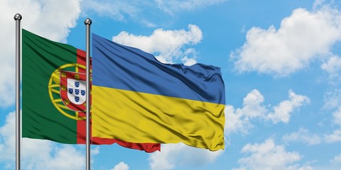 Portugal and Ukraine flag waving in the wind against white cloudy blue sky together. Diplomacy concept, international relations.