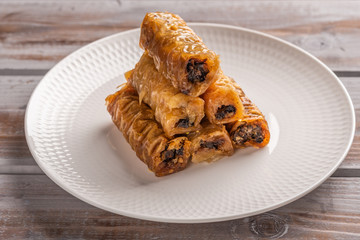 Traditional greek pastries saragli in a white plate with on a wooden background