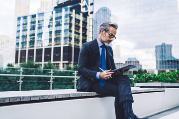 Adult businessman holding tablet and stylus on background of New York