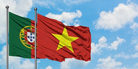 Portugal and Vietnam flag waving in the wind against white cloudy blue sky together. Diplomacy concept, international relations.