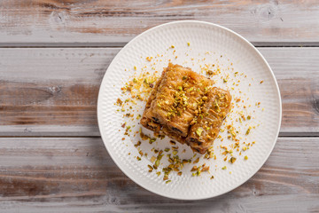Traditional greek pastries saragli in a white plate on a wooden background