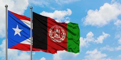 Puerto Rico and Afghanistan flag waving in the wind against white cloudy blue sky together. Diplomacy concept, international relations.
