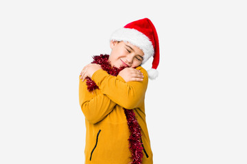 Little boy celebrating christmas day wearing a santa hat isolated hugs, smiling carefree and happy.