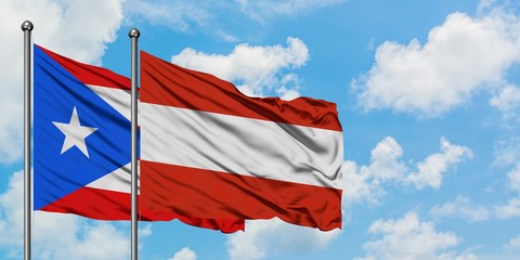 Puerto Rico and Austria flag waving in the wind against white cloudy blue sky together. Diplomacy concept, international relations.