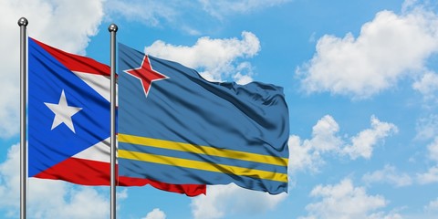 Puerto Rico and Aruba flag waving in the wind against white cloudy blue sky together. Diplomacy concept, international relations.