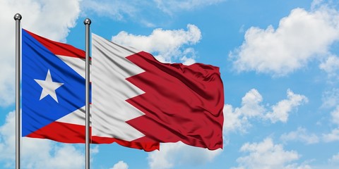 Puerto Rico and Bahrain flag waving in the wind against white cloudy blue sky together. Diplomacy concept, international relations.