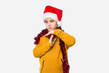 Little boy celebrating christmas day wearing a santa hat isolated showing a timeout gesture.