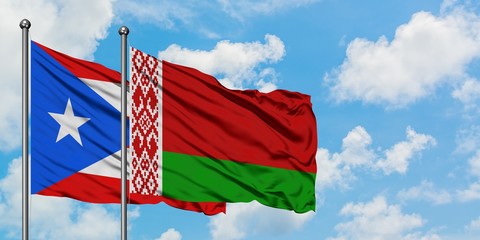 Puerto Rico and Belarus flag waving in the wind against white cloudy blue sky together. Diplomacy concept, international relations.