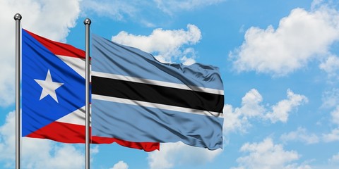 Puerto Rico and Botswana flag waving in the wind against white cloudy blue sky together. Diplomacy concept, international relations.
