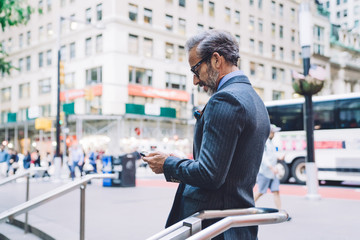 Mature stylish businessman using mobile phone outside