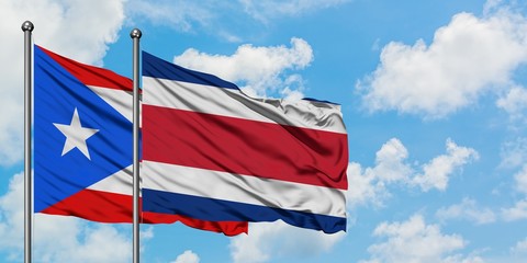 Puerto Rico and Costa Rica flag waving in the wind against white cloudy blue sky together. Diplomacy concept, international relations.