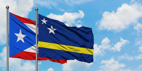 Puerto Rico and Curacao flag waving in the wind against white cloudy blue sky together. Diplomacy concept, international relations.