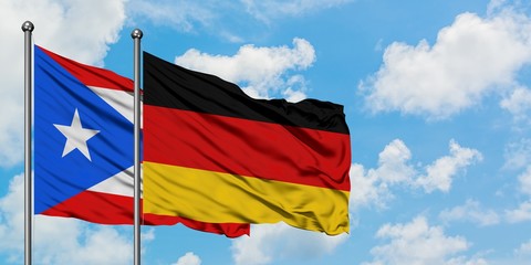 Puerto Rico and Germany flag waving in the wind against white cloudy blue sky together. Diplomacy concept, international relations.