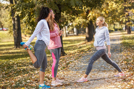Group of female friends stretching and relaxing after running .Autumn season.	