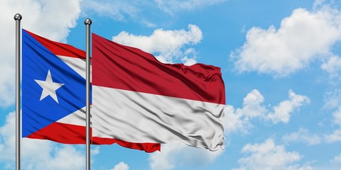 Puerto Rico and Indonesia flag waving in the wind against white cloudy blue sky together. Diplomacy concept, international relations.