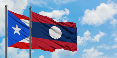 Puerto Rico and Laos flag waving in the wind against white cloudy blue sky together. Diplomacy concept, international relations.