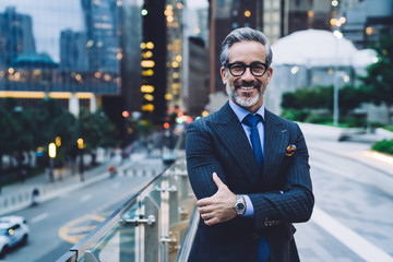 Middle aged businessman with arms crossed against evening New York street