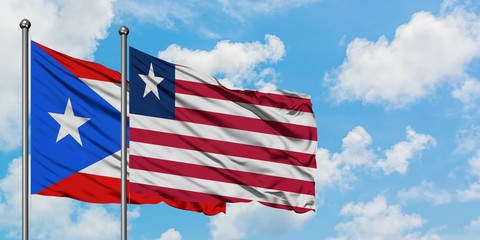 Puerto Rico and Liberia flag waving in the wind against white cloudy blue sky together. Diplomacy concept, international relations.