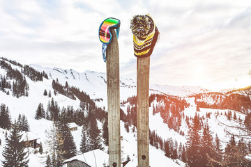 Vintage wood skies with winter cap and sunglasses - Snow mountain view with sport gear at sunset - Travel, retro and holidays concept - Focus on objects