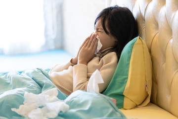 Sick child girl have a cold,blowing nose in paper handkerchief in bedroom,flu or the weather is changing,asian female teenage sneezing in a tissue,concept of allergic rhinitis,hay fever,health care - obrazy, fototapety, plakaty