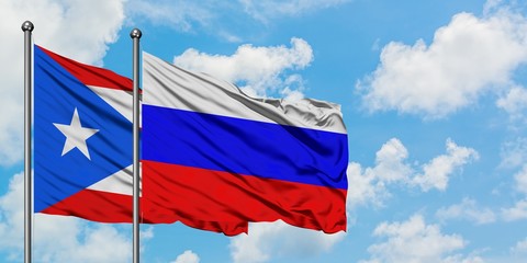 Puerto Rico and Russia flag waving in the wind against white cloudy blue sky together. Diplomacy concept, international relations.