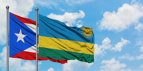 Puerto Rico and Rwanda flag waving in the wind against white cloudy blue sky together. Diplomacy concept, international relations.