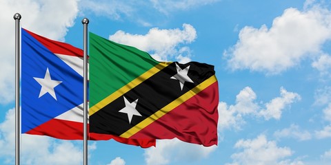 Puerto Rico and Saint Kitts And Nevis flag waving in the wind against white cloudy blue sky together. Diplomacy concept, international relations.