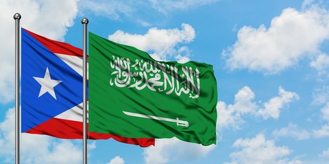 Puerto Rico and Saudi Arabia flag waving in the wind against white cloudy blue sky together. Diplomacy concept, international relations.