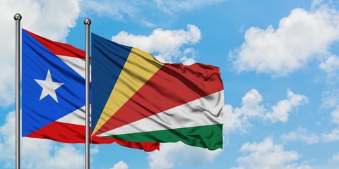 Puerto Rico and Seychelles flag waving in the wind against white cloudy blue sky together. Diplomacy concept, international relations.