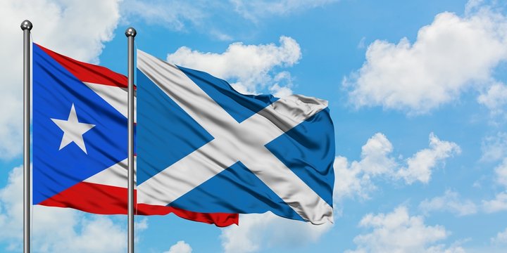 Puerto Rico and Scotland flag waving in the wind against white cloudy blue sky together. Diplomacy concept, international relations.
